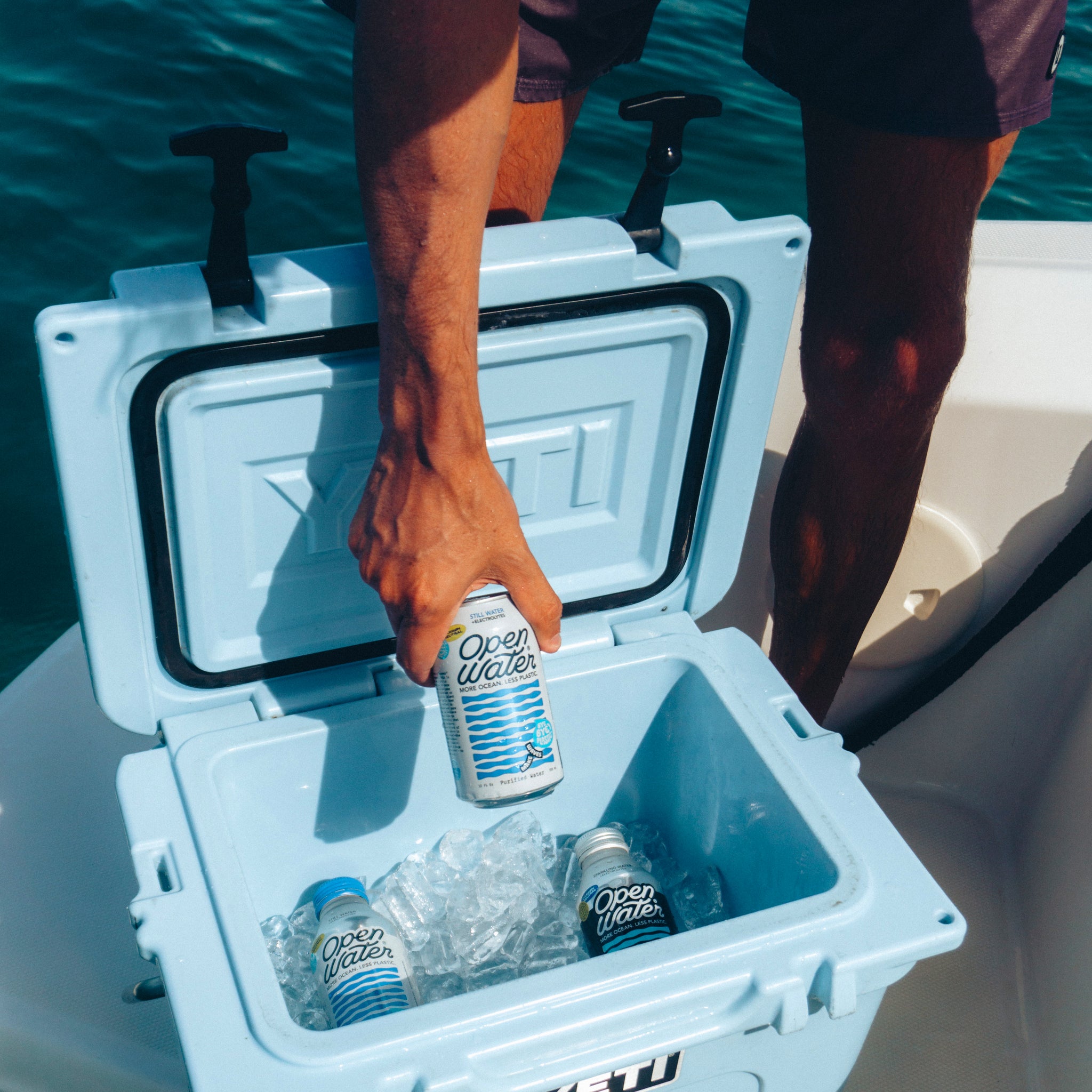 person grabbing canned water out of cold cooler